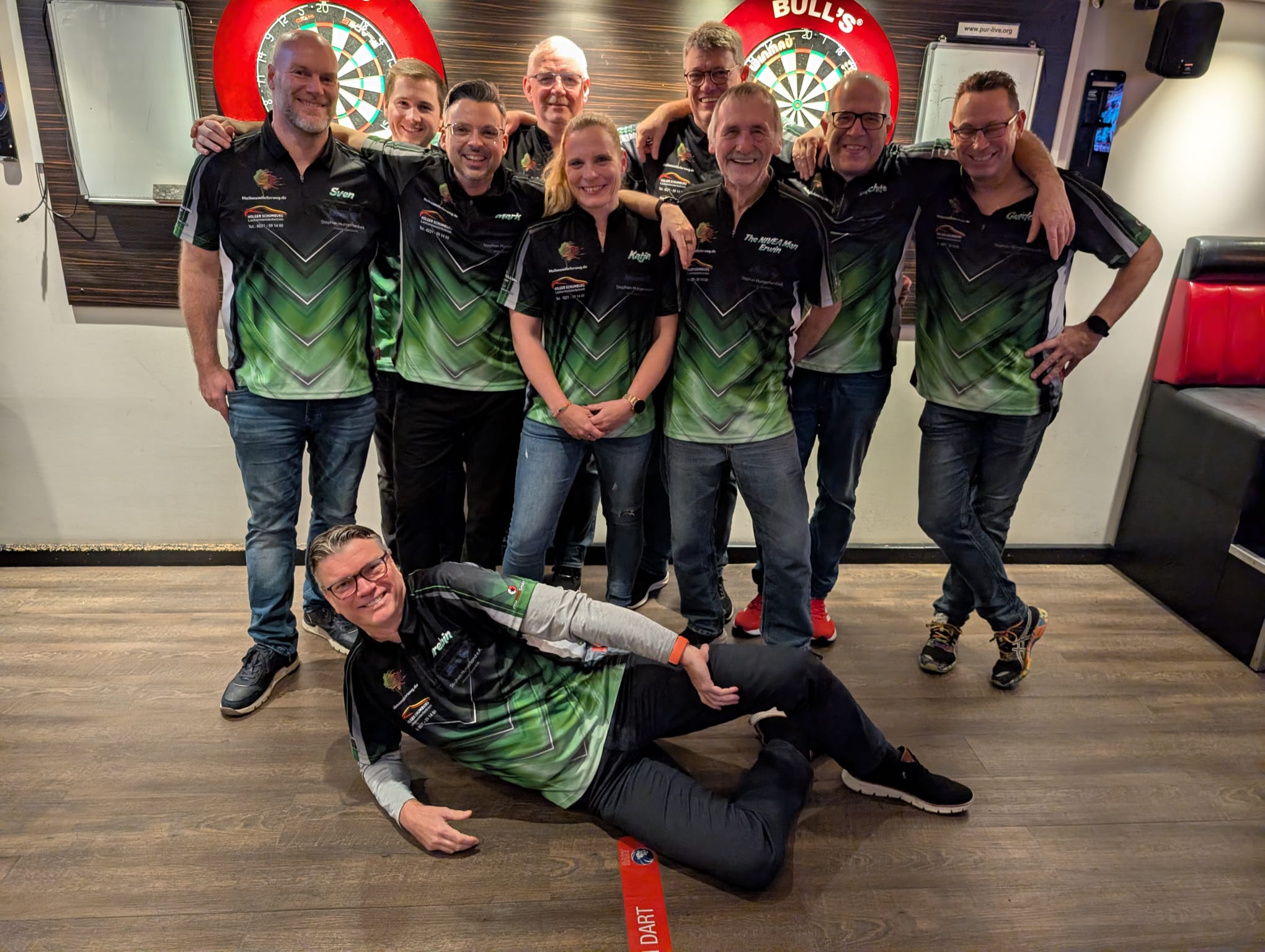 Gruppenfoto des Stadtliga-Teams von LSD Worringen vor den Dartboards im Pur-Live.